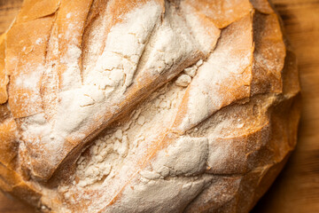 Fresh round bread made of wheat flour on a wooden background. Close-up. View from above.