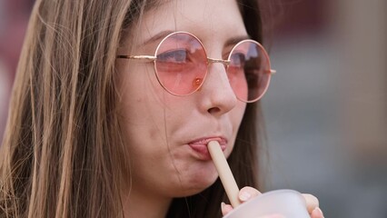 Pensive happy woman sipping a milkshake in the street