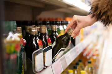 オリーブオイルを選ぶ女性の手元