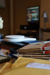 Envelopes and parcels with soft-focused weighing scales and a computer in the background at home.