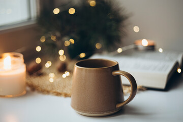 Christmas cozy home background with candle and cup on windowsill, copy space.
