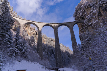 Scenic view of famous railway Landwasser Viaduct at Albula Valley in the Swiss Alps on a snowy...