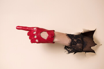 A woman's hand in a leather glove is pointing with her index finger