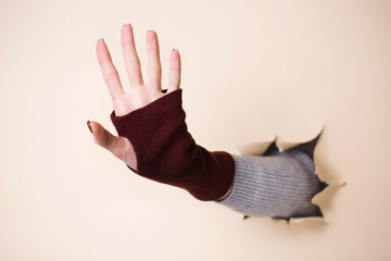 Female hand in a knitted burgundy mitten showing 5 fingers