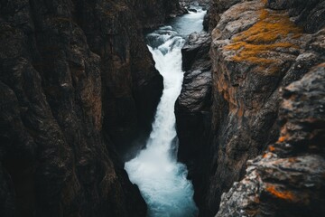 Obraz premium Powerful Waterfall Plunges Through Dark Rocky Gorge