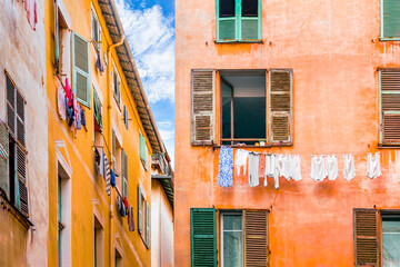 NICE, FRANCE: narrow alley and colorful facades of traditional houses with laundry hanging from the windows