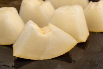 pieces of sliced ripe and sweet melon on a black surface