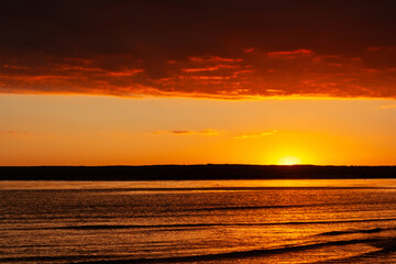 sunset over a body of water with a mountain