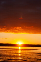 Naklejka premium sunset over a body of water with a mountain