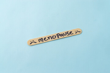 Menopause word on ice cream stick with a blue background.