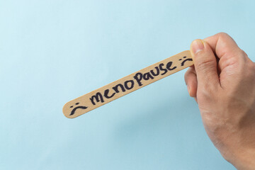 Menopause word on ice cream stick with a blue background.