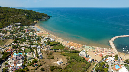 Aerial view of the beach of Peschici bay, in Puglia, Italy, on the coast of the Adriatic Sea. It's a tourist destination in Gargano, in the province of Foggia. There are many beach clubs and umbrellas