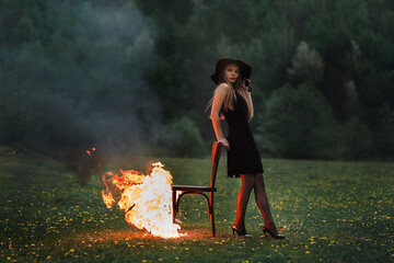 a girl is standing on a burning chair, the fire has engulfed the chair, she is in a calm state