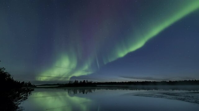 Auroras starting to dance at dusk above a still lake