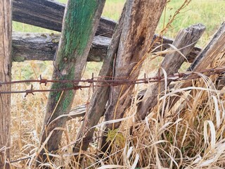 old sagging fence made of boards and barbed wire