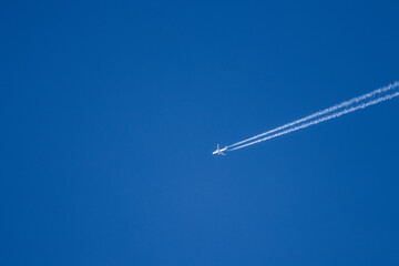 Un avión surca un cielo azul claro, dejando rastros de estelas blancas. Una escena que transmite libertad, exploración y tranquilidad en las alturas.
