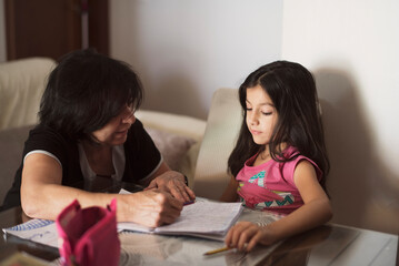 Grandmother at home helps granddaughter to do homework