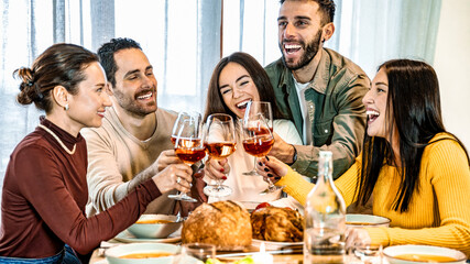 Group of smiling friends enjoying dinner at home - Happy family having dining party together - Life style concept with guys and girls eating meal and drinking red wine - Food and beverage lifestyle