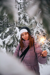 A young girl with a sparkler in the winter forest