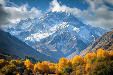 Snowcapped mountains rise majestically above autumn foliage under a clear blue sky