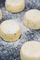 Frozen syrniki (cottage cheese pancakes) flavored with creamy cheese and dill on a dark black background, semi-finished and ready for cooking. 