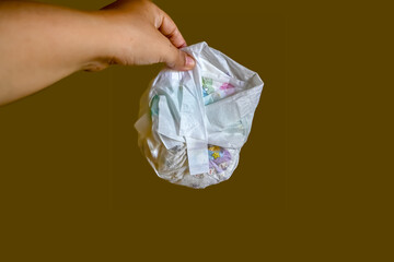 Hand holding used baby diaper on isolated brown background.