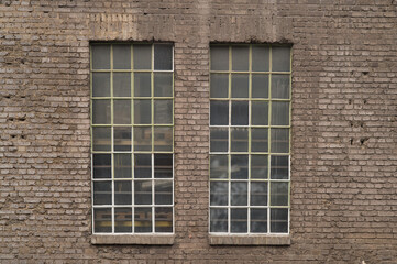 Two industrial windows showing pallets inside an old brick wall