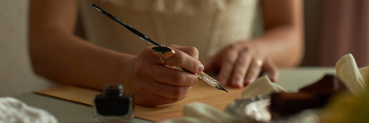 Header closeup of classic young lady writing letter with focus on female hands holding intricate...