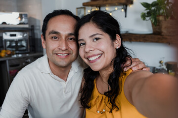 latin young couple taking a photo selfie using mobile phone at home in Mexico Latin America, portrait of hispanic people having fun	