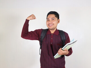 Young winner smart asian boy student he wear maroon t-shirt casual clothes backpack bag hold books showing hand biceps muscles isolated on white background. High school university college concept