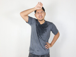Asian man sweating while wiping sweat from his forehead with a face that looks uncomfortable