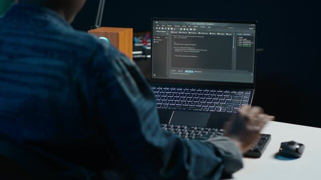 Software developer writes code on laptop screen while in apartment office using Java programming languages. Programmer remotely working on fixing database errors while working from home, camera A