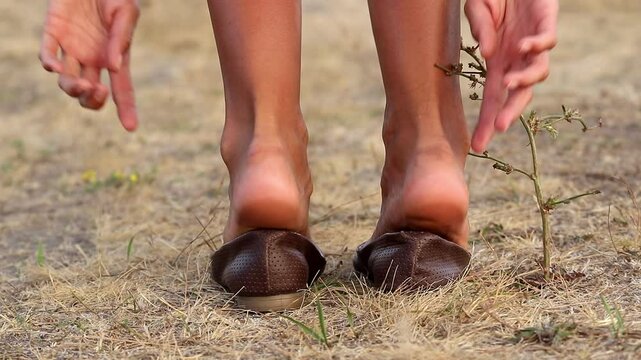 The girl puts on her shoes.Women's feet without shoes.Walking barefoot on the grass in hot summer.