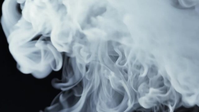 Subtelny biały dym rozprzestrzeniający się na czarnym tle, jego miękkie, pofalowane kształty tworzą dynamiczny i intrygujący wizualny efekt.