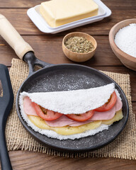 Traditional brazilian cheese, ham and tomato stuffed tapioca on a pan with ingredients