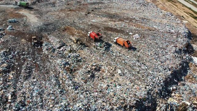 Area of landfill littered with discarded items. Excavator and a lorry working at the city landfill. Industrial waste disposal. 4k footage