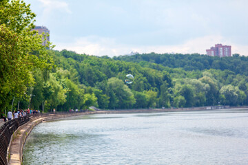 soap bubble over the river against the background of the park