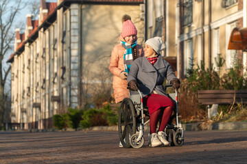 disabled girl, wheelchair, family walk in the park with a disabled woman, mother with daughter, autumn, winter in Europe