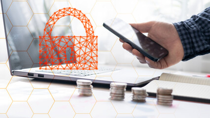 A man is holding a cell phone and a laptop with a red lock on the laptop. Concept of security and protection, as the lock symbolizes the need to safeguard one's personal information and data