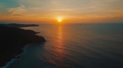 Fototapeta premium Coastal Sunset Over Ocean With Silhouetted Land