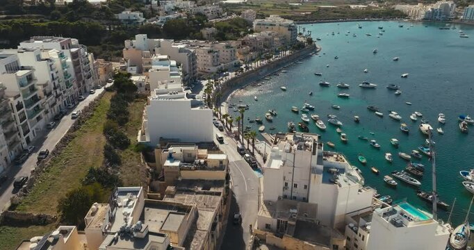 Aerial view of the marina in Bugibba, Malta. Beautiful cityscape of a tourist city in the Mediterranean Sea, yachts and boats moored on the embankment, travel and tourism in Europe. High quality 4k 