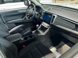 The inside of a pristine white car featuring stylish black seats along with a sleek steering wheel, providing a modern look and feel for a comfortable driving experience