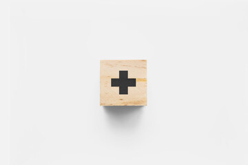 + (Plus) wooden cube on white background