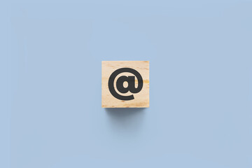 @ (at) wooden cube on blue background