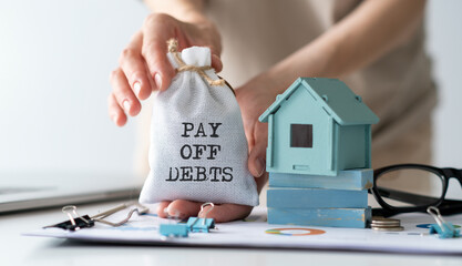 Pay Off Debts text on bag ind hands and miniature house.