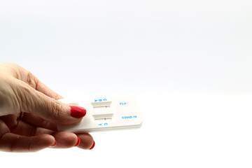 Woman's hand holding a coronavirus and flu test on white background.