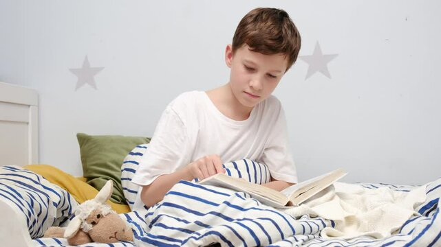 A boy reads peacefully in bed with his favorite stuffed animal beside him at night