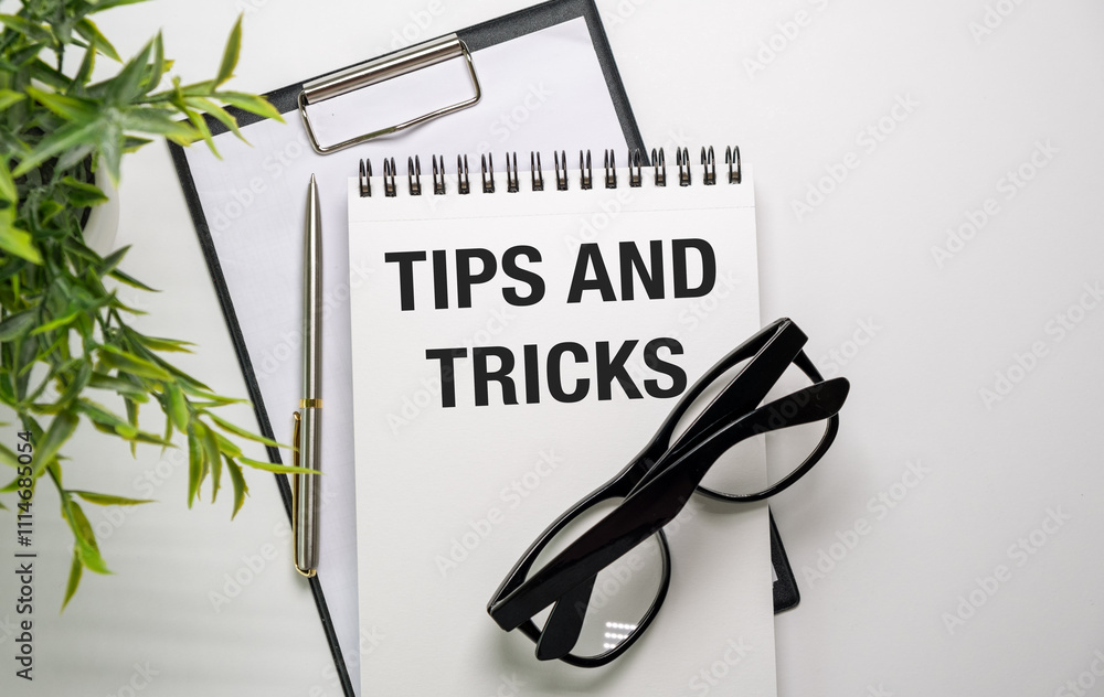 Poster magnifying glass and notebook with tips and tricks word with copy space on wooden table. tips and tr