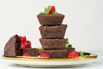 Chocolate brownies stacked with the top adorned by a red juicy cherry and mint leaves