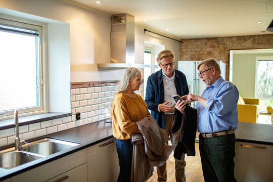 Elderly couple consulting with real estate agent in new home kitchen